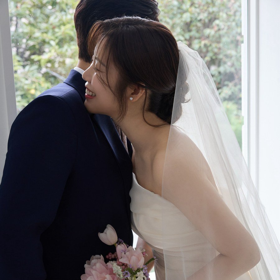 Lindsey embracing Jake by a window, holding a bouquet